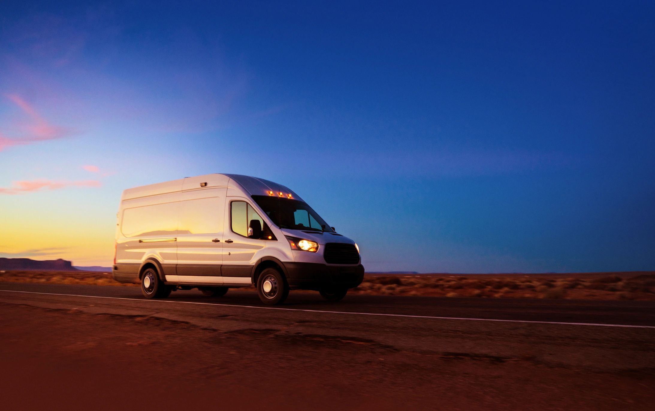 A white transport van traveling at sunset